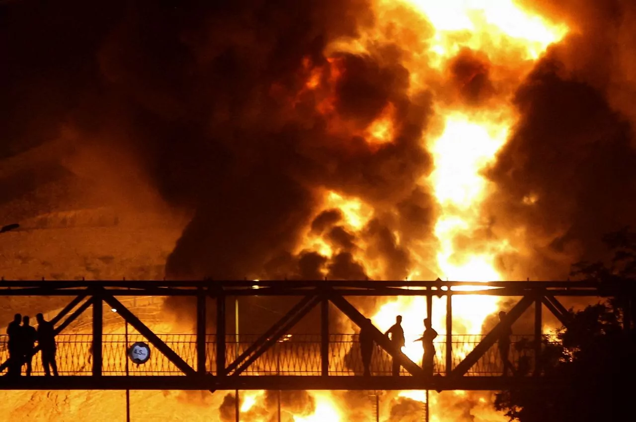 People watch flames from an Israeli attack on an oil depot in Tehran, Iran on Sunday. Majid Asgaripour/WANA News Agency via Reuters